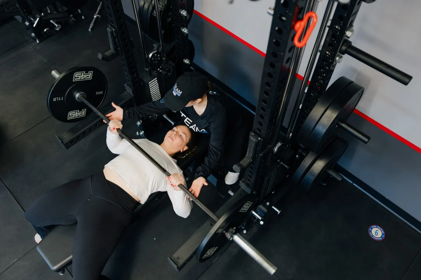 Coach spotting a member through a barbell bench press set