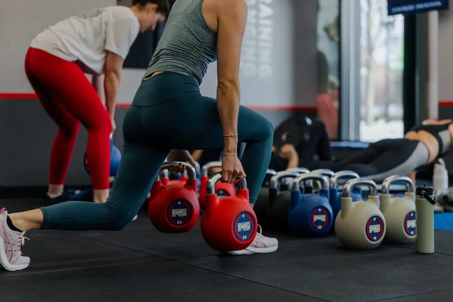 Members at F45 Training North Weston working through loaded reverse lunges at their stations.