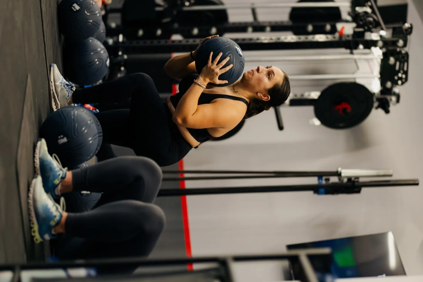 Members doing medicine-ball sit-ups side by side at floor stations